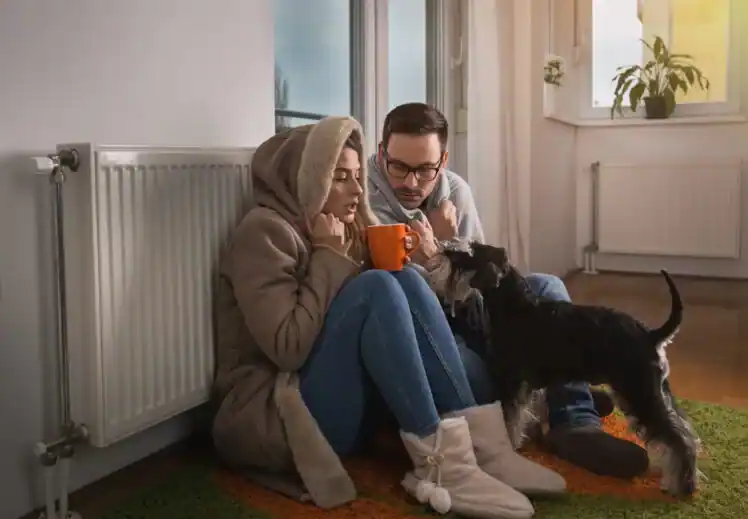 Paar wärmt sich in Decken an einem kalten Heizkörper