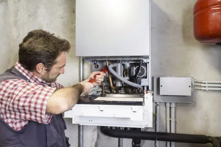 Installateur arbeitet an der geöffneten Gastherme